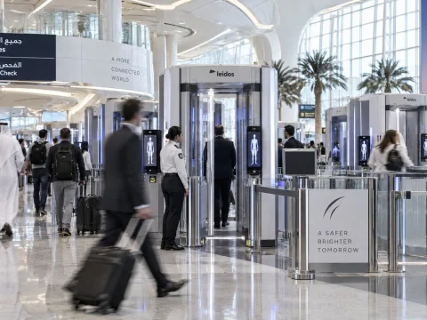 Travelers passing through automatic security gates in a bright modern airport terminal