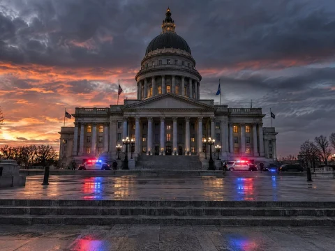 Domed parliament building at dusk with flashing police lights in the foreground