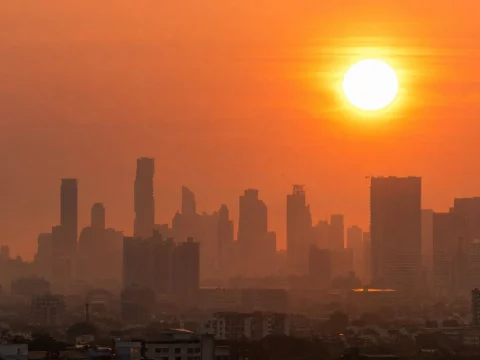 City skyline silhouette under a blazing orange sun and hazy sky during a heatwave
