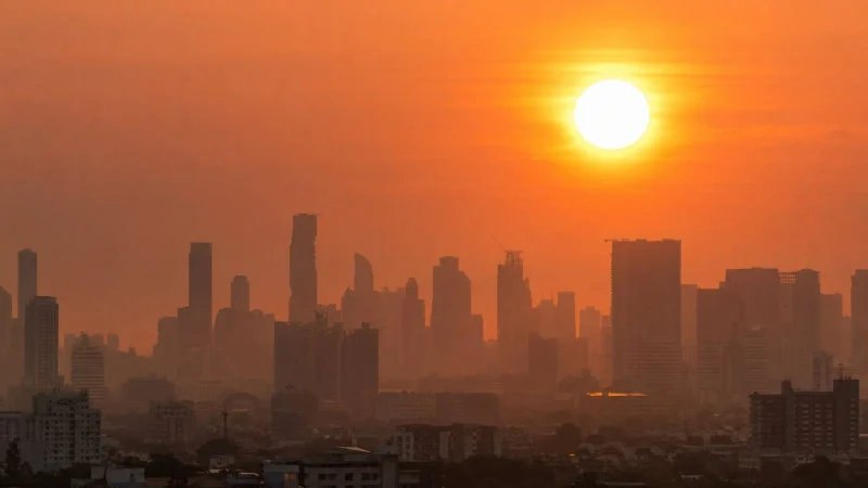 City skyline silhouette under a blazing orange sun and hazy sky during a heatwave
